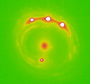 Immagine della galassia lente Rx J1131-1231, al centro, dove si troverebbero migliaia di pianeti. i quattro punti luminosi all'esterno sono gli ingrandimenti della galassia obiettivo dell'osservazione, osservabili grazie alla lente gravitazionale al centro. | University of Oklahoma